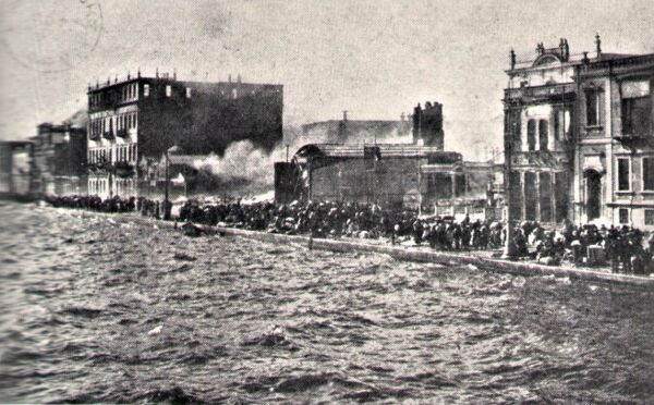 Buildings on fire and people trapped between the fire and the sea.